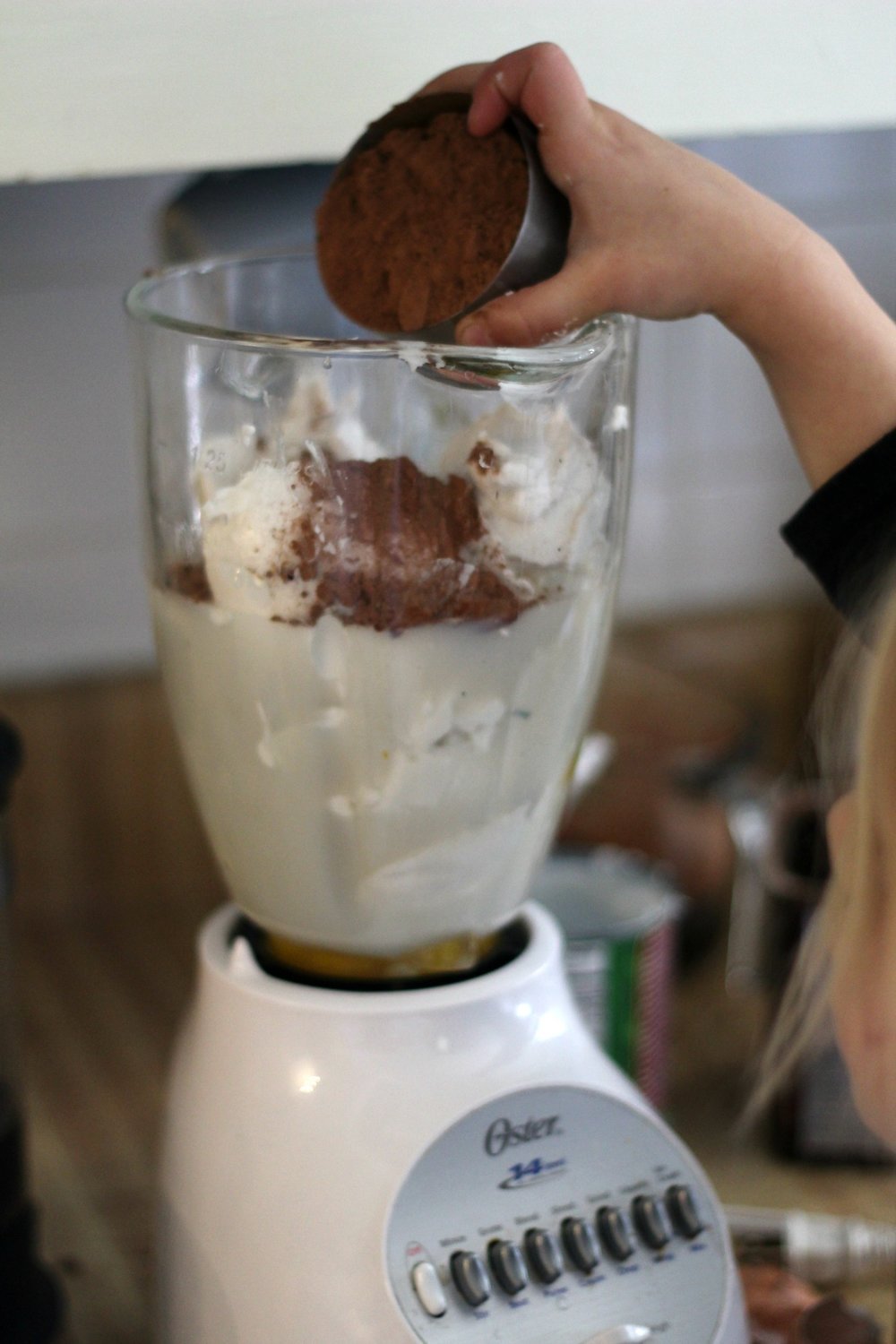 making homemade chocolate ice cream in a blender. Adding cocoa powder to remaining ingredients