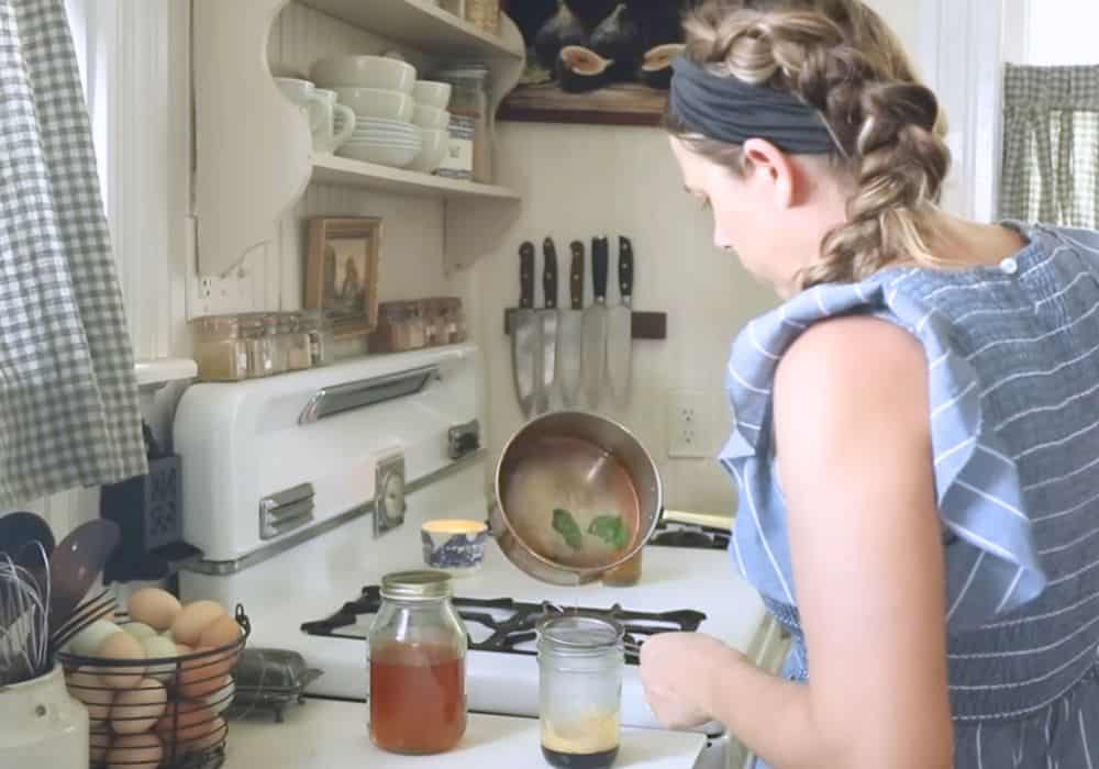 Woman pouring lavender syrup into a glass jar with espresso.