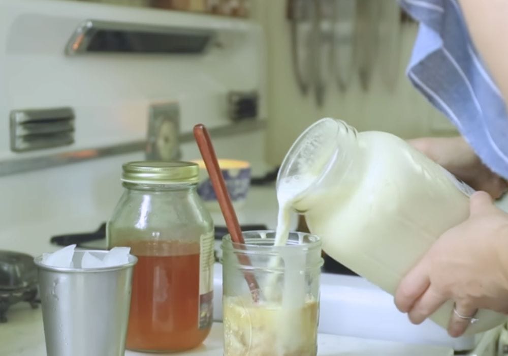 Woman adding milk to a gass mason jar. 