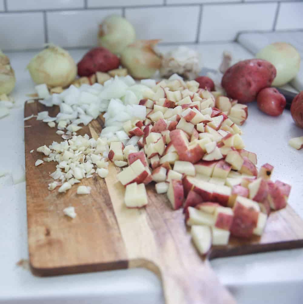 potatoes and onions chopped on a wood cutting board on top a ikea quarts countertop
