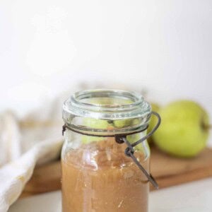 Homemade applesauce in a vintage jar on a white countertop.