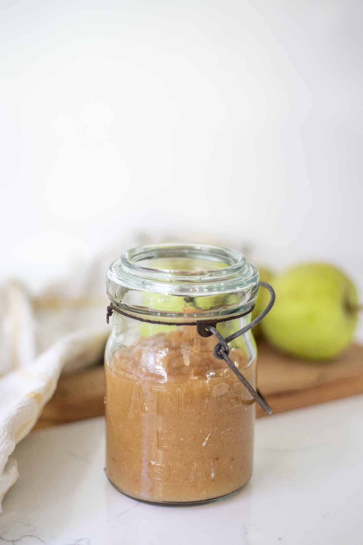 Homemade applesauce in a vintage jar on a white countertop.