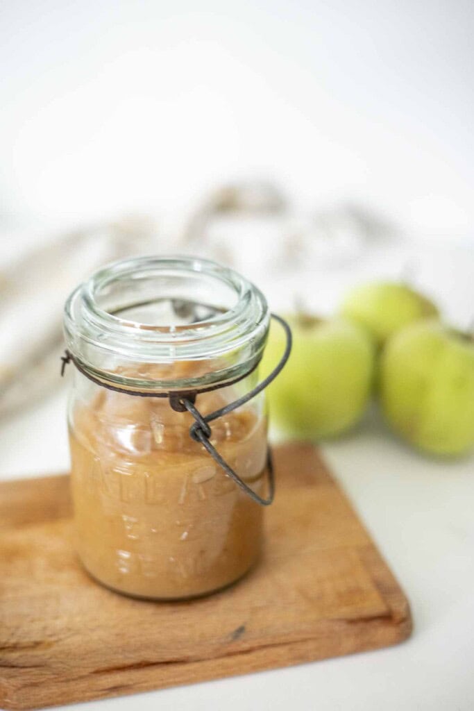 Instant Pot applesauce in a vintage jar on a cutting board.