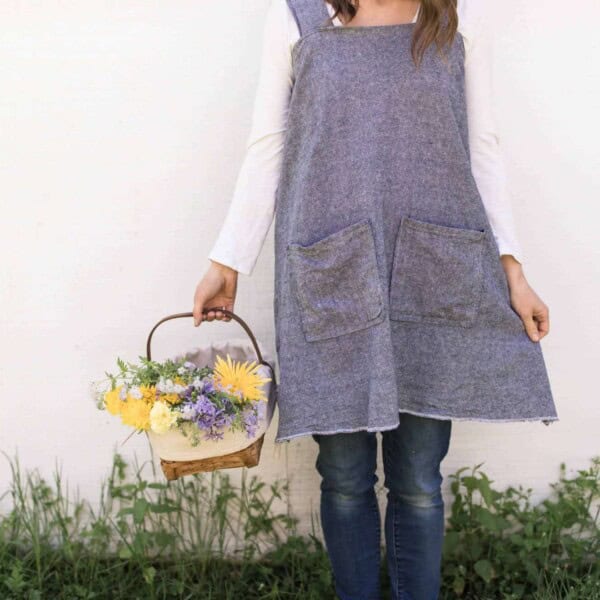 women with a DIY apron holding a basket of flowers