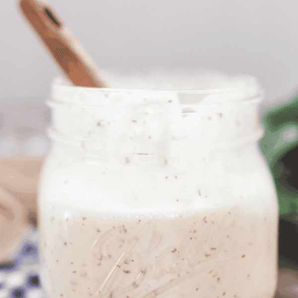 homemade ranch dressing in a mason jar with a wooden spoon in the jar on top a wood table