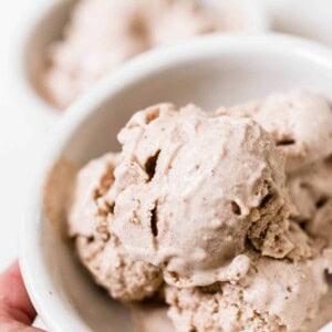 hand holding a bowl of pumpkin spice ice cream sweetened with dates