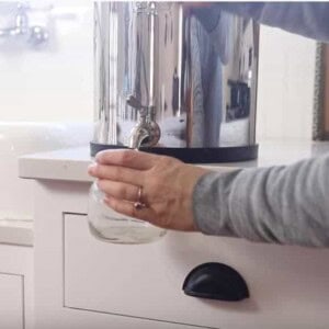 women filling a mason jar of filtered water from a Berkey water filter