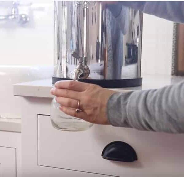 women filling a mason jar of filtered water from a Berkey water filter