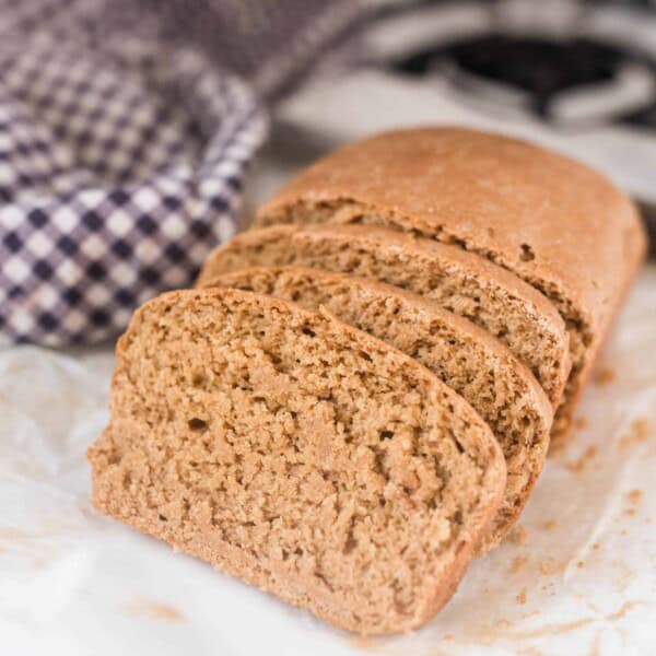 einkorn sandwich bread sliced on a stove top with a blue and white checked towel in the background