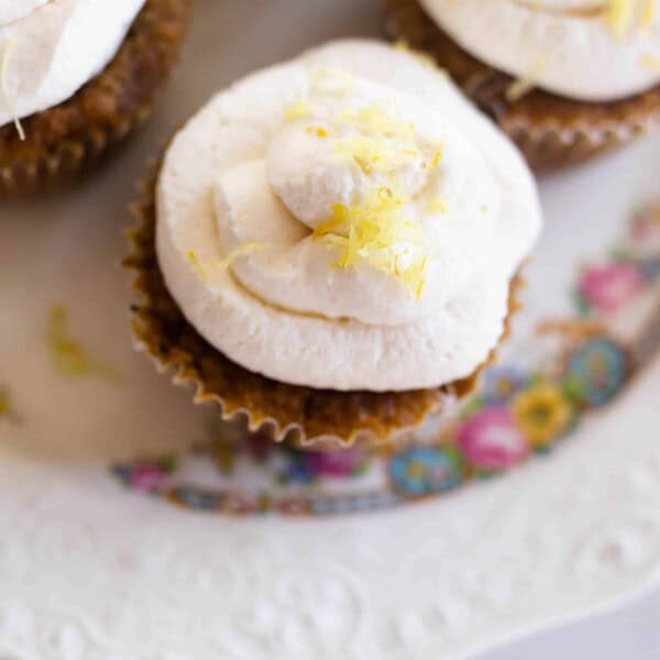 overhead shot of muffins with lemon whipped cream frosting topped with lemon zest.