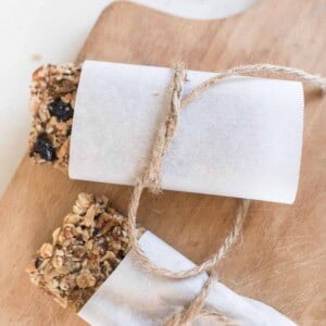 rustic granola bars wrapped in parchment paper and tied with twine on a cutting board.