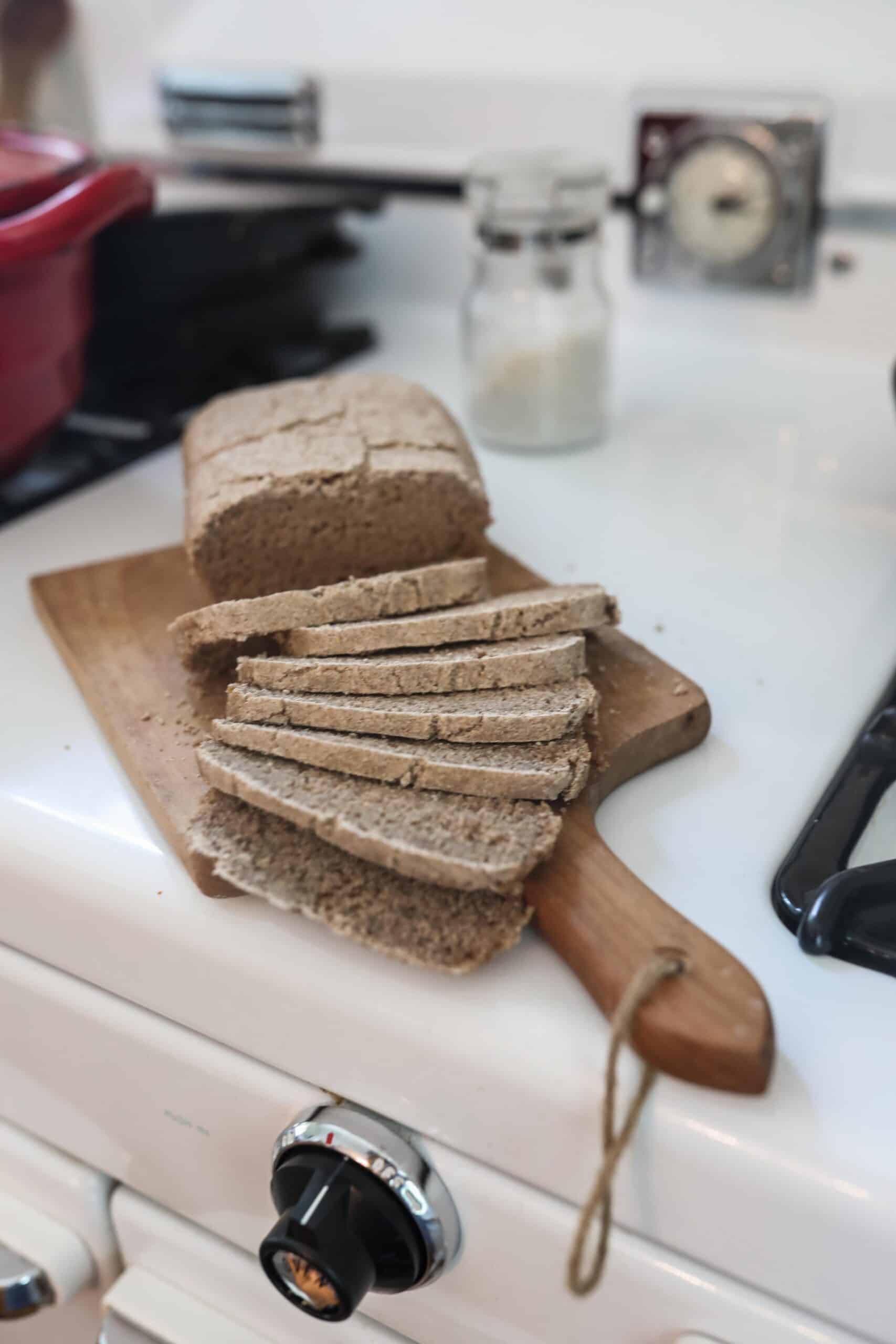 loaf of sourdough rye bread on a wood cutting board on an antique stove