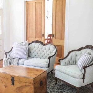 victorian couches painted a soft green in a living room with a wood chest as a coffee table