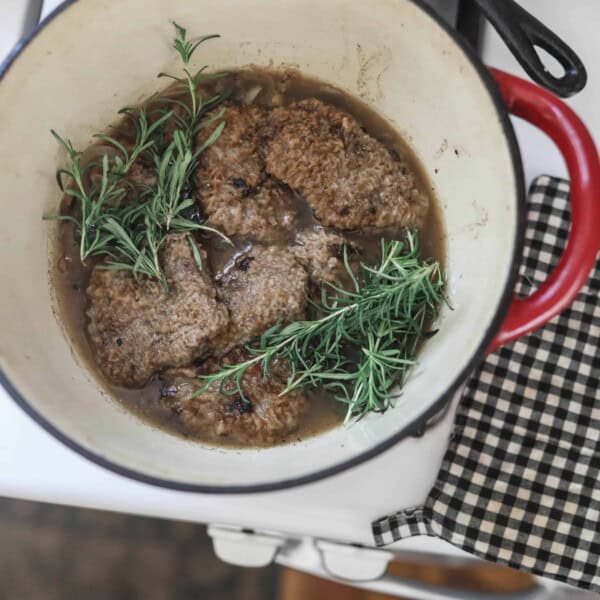 round steak with fresh rosemary, onions, and mushrooms in a red dutch oven