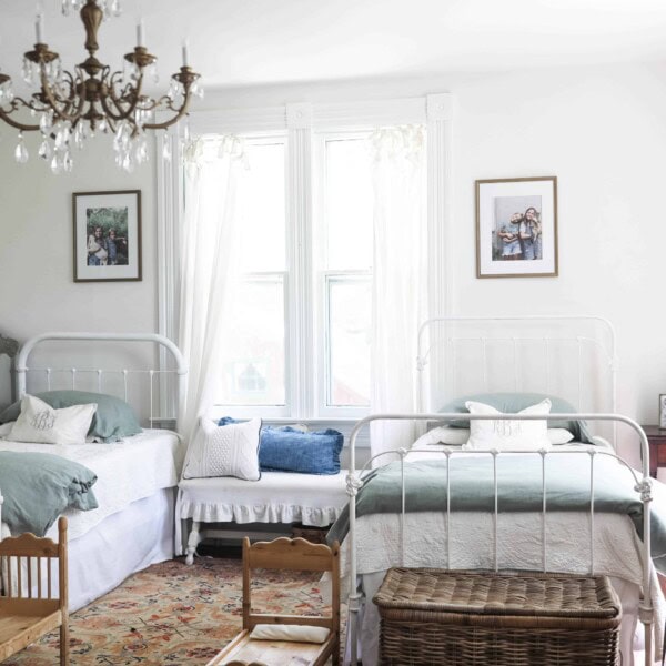 victorian farmhouse girls room with two twin beds and a gold chandelier