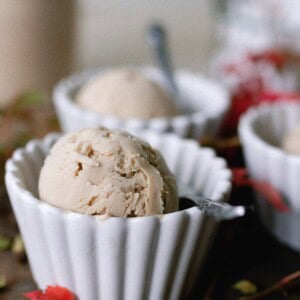 chai ice cream in white bowls with spoons. Red fall leaves are set on the table.