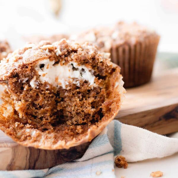 sourdough carrot muffin cut in half on a cutting board with more muffins in the background