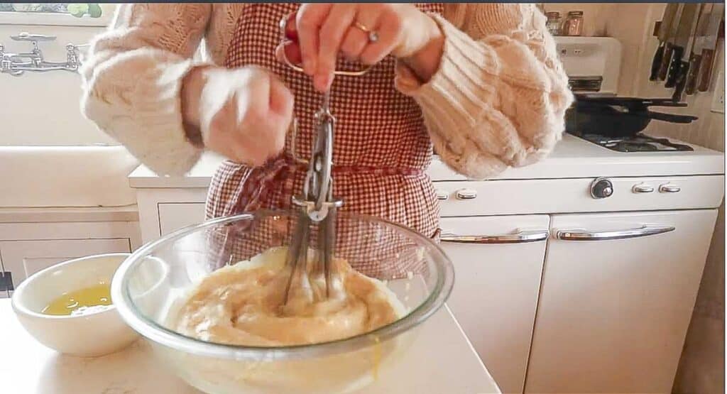 woman mixing together ingredients in a glass bowl.