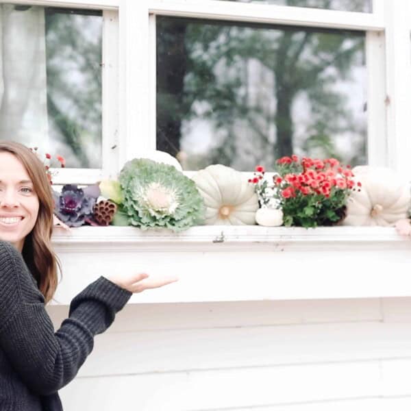 women standing next to a fall window box full of beautiful fall foliage