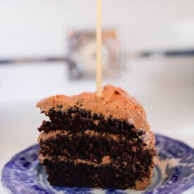 slice of sourdough chocolate cake with chocolate frosting on a blue and white plate on a vintage 1940s stove