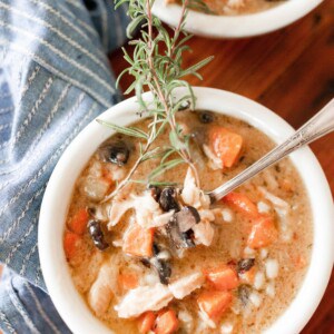 overhead photo of chicken Marsala Soup in two white bowls with a fresh spring of rosemary on top