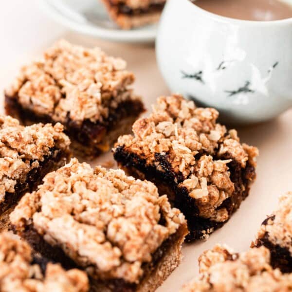 date squares on parchment paper with a mug of coffee behind