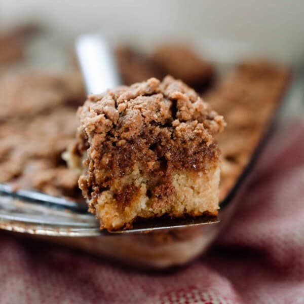 slice of coffee cake resting on top of baking dish of cake on a red and white towel