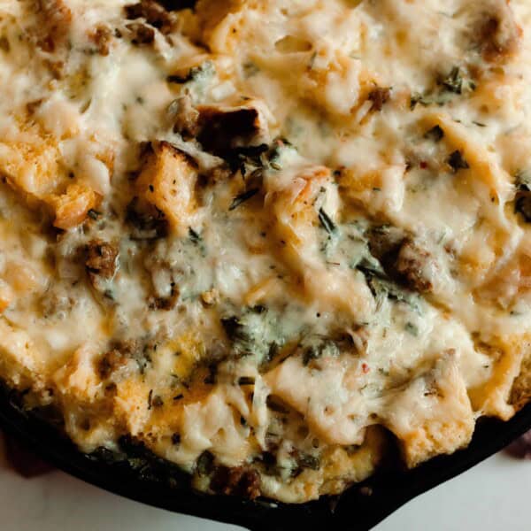 sourdough breakfast strata with sausage, cheese, and herbs in a cast iron skillet