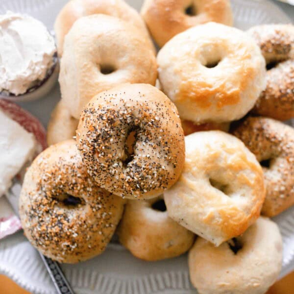 sourdough bagels on a white platter with a cream cheese on a plate