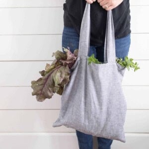 women wearing a black shirt and jeans holding a DIY tote bag full of lettuce