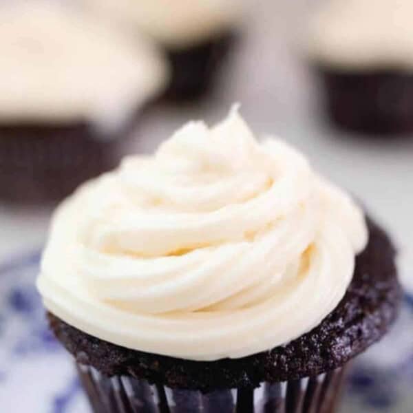 sourdough cupcake with cream cheese buttercream frosting on a white and blue antique plate