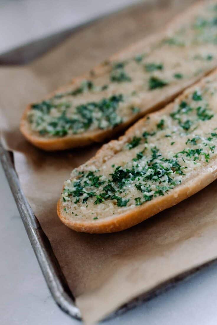 sourdough French bread cut in half and covered with garlic butter baked in the oven on parchment lined baking sheets