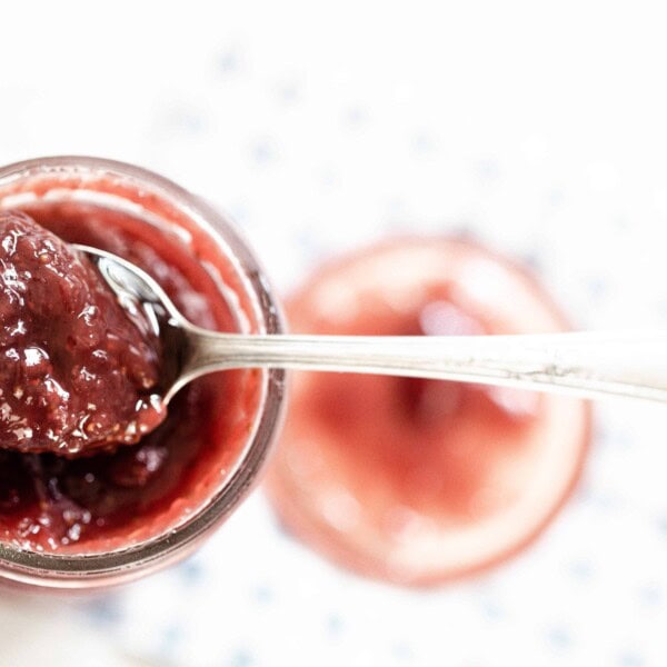 jar of strawberry jam with a spoon full of jam resting on the rim.