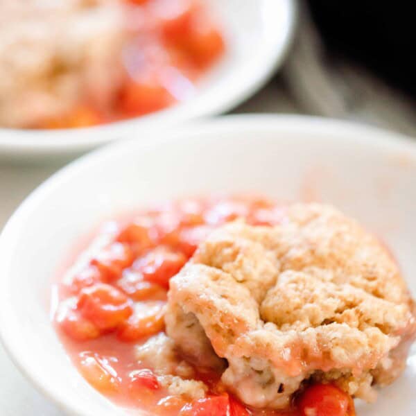 sourdough cherry cobbler in a white bowl with another bowl of cobbler in the background