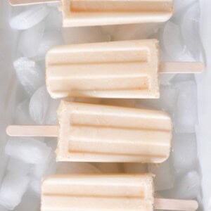 overhead photo of four orange creamsicle popsicles in a white dish full of ice