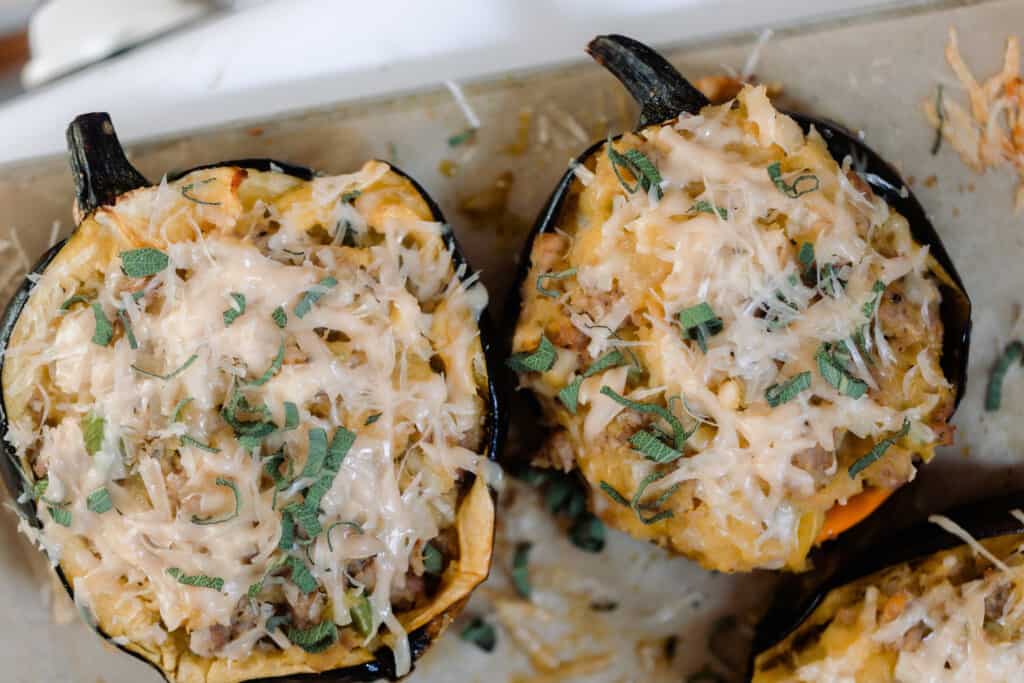 Two halves of acorn squash stuffed with sausage and apples and topped with parmesan cheese.