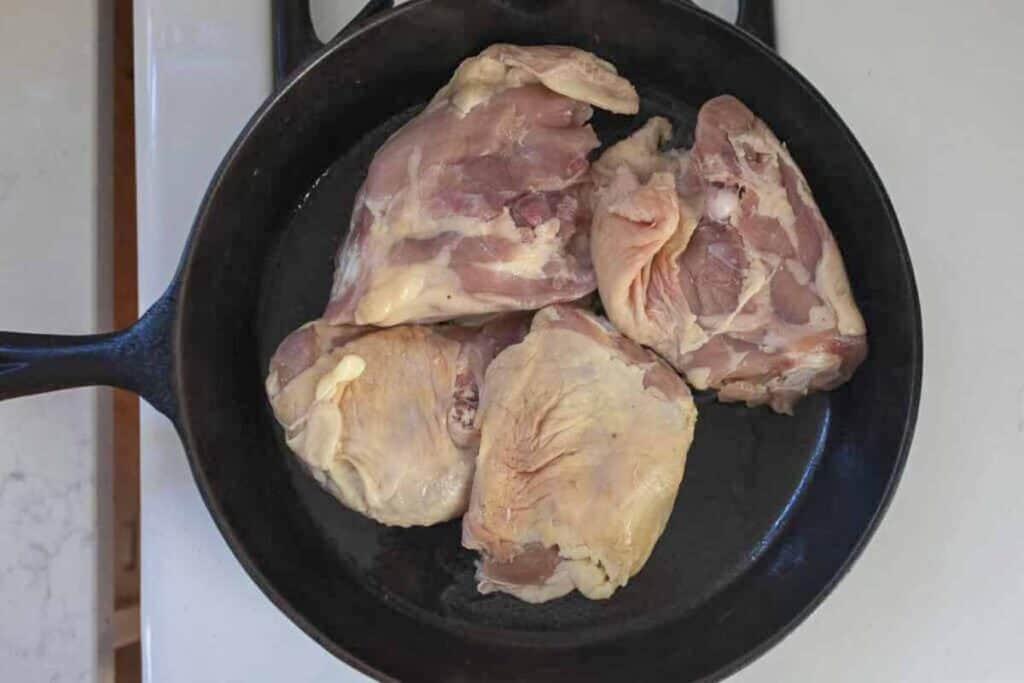 raw chicken in a cast iron skillet.