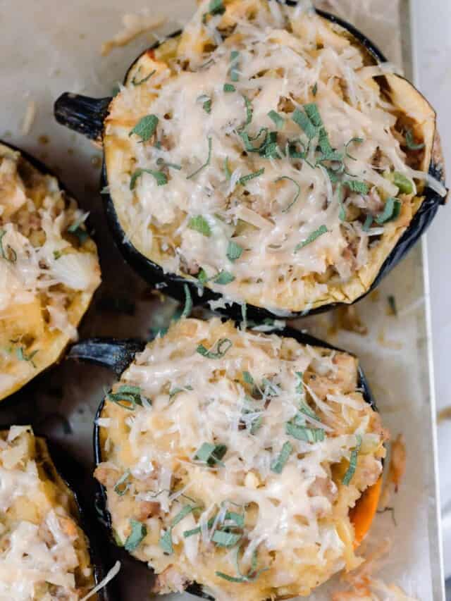 overhead photo of Sausage and Apple Stuffed Acorn Squash topped with parmesan and fresh sage on parchment paper