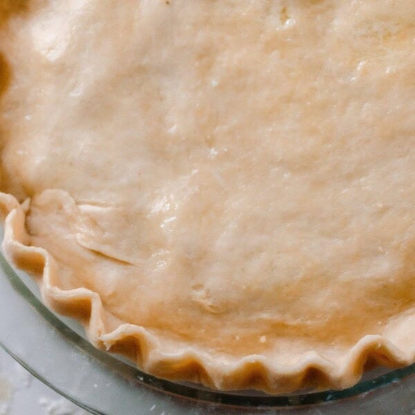 Overhead photo of einkorn pie crust used in a pie with double crust. The pie is in a glass pie dish on a white and gray quartz counter