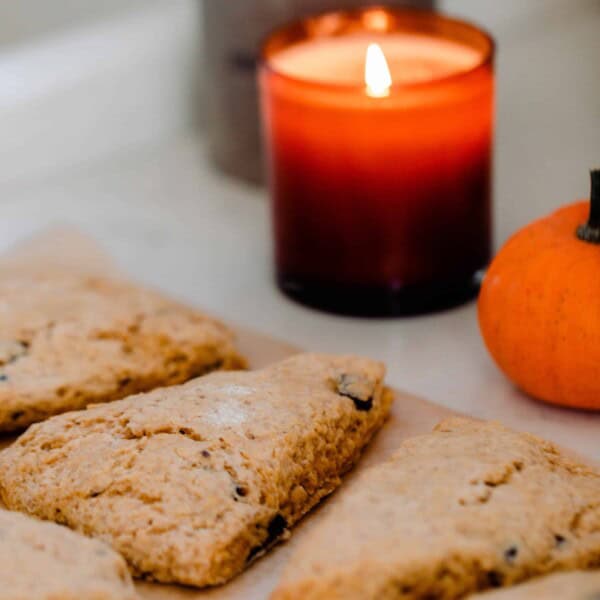 sourdough pumpkin scones cut into triangles on a quarts counter top with lit candles in the background