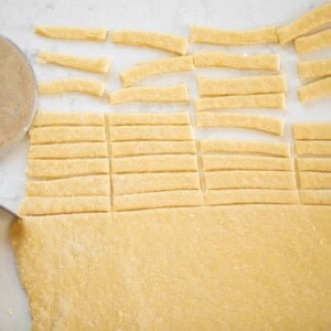 homemade noodles rolled out and half the dough is cut into small noodles for soup