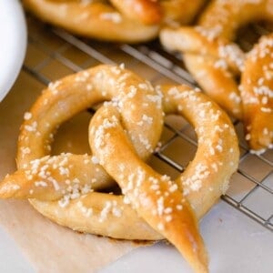 sourdough pretzel topped with course salt on a wire cooling wrack with more pretzels