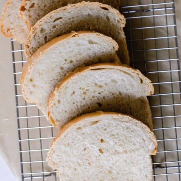 six slices of sourdough sandwich bread spread out on a wire rack over parchment paper