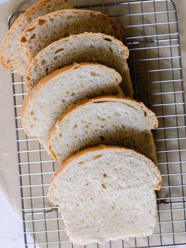 six slices of sourdough sandwich bread spread out on a wire rack over parchment paper