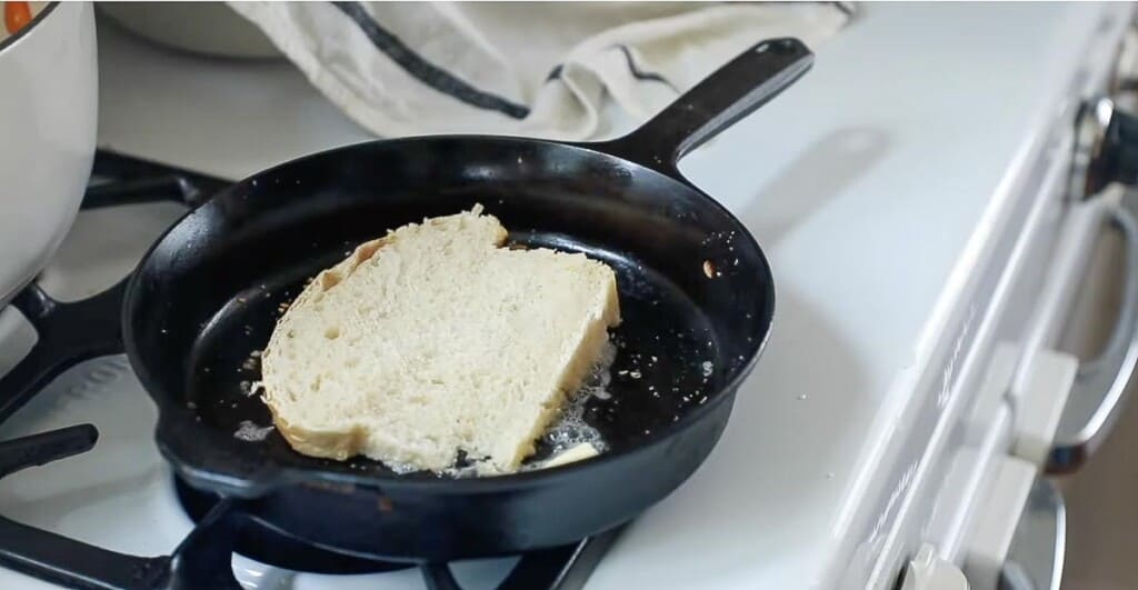 A slice of bread buttered and in a cast iron skillet.