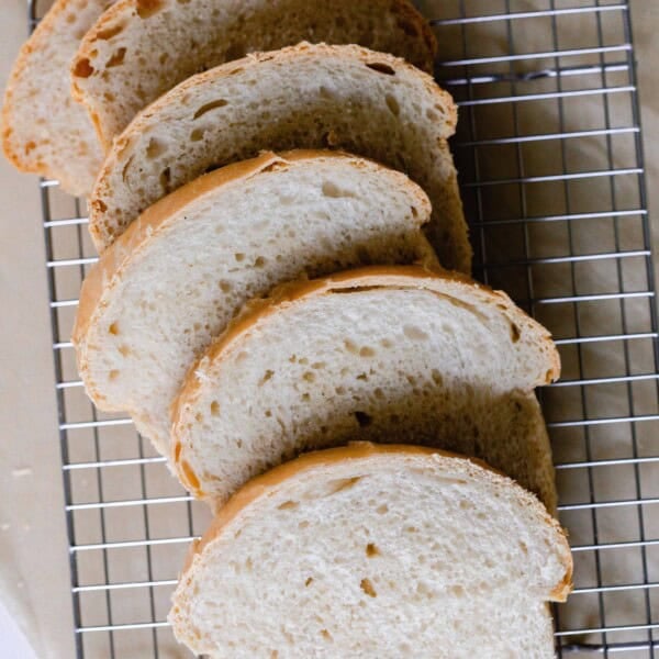 six slices of sourdough sandwich bread spread out on a wire rack over parchment paper