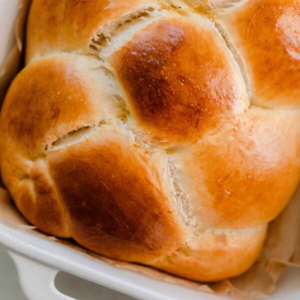 close up overhead photo of sourdough challah in a white baking dish