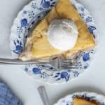 A slice of sourdough apple cobbler with a scoop of ice cream on top on a small saucer plate.