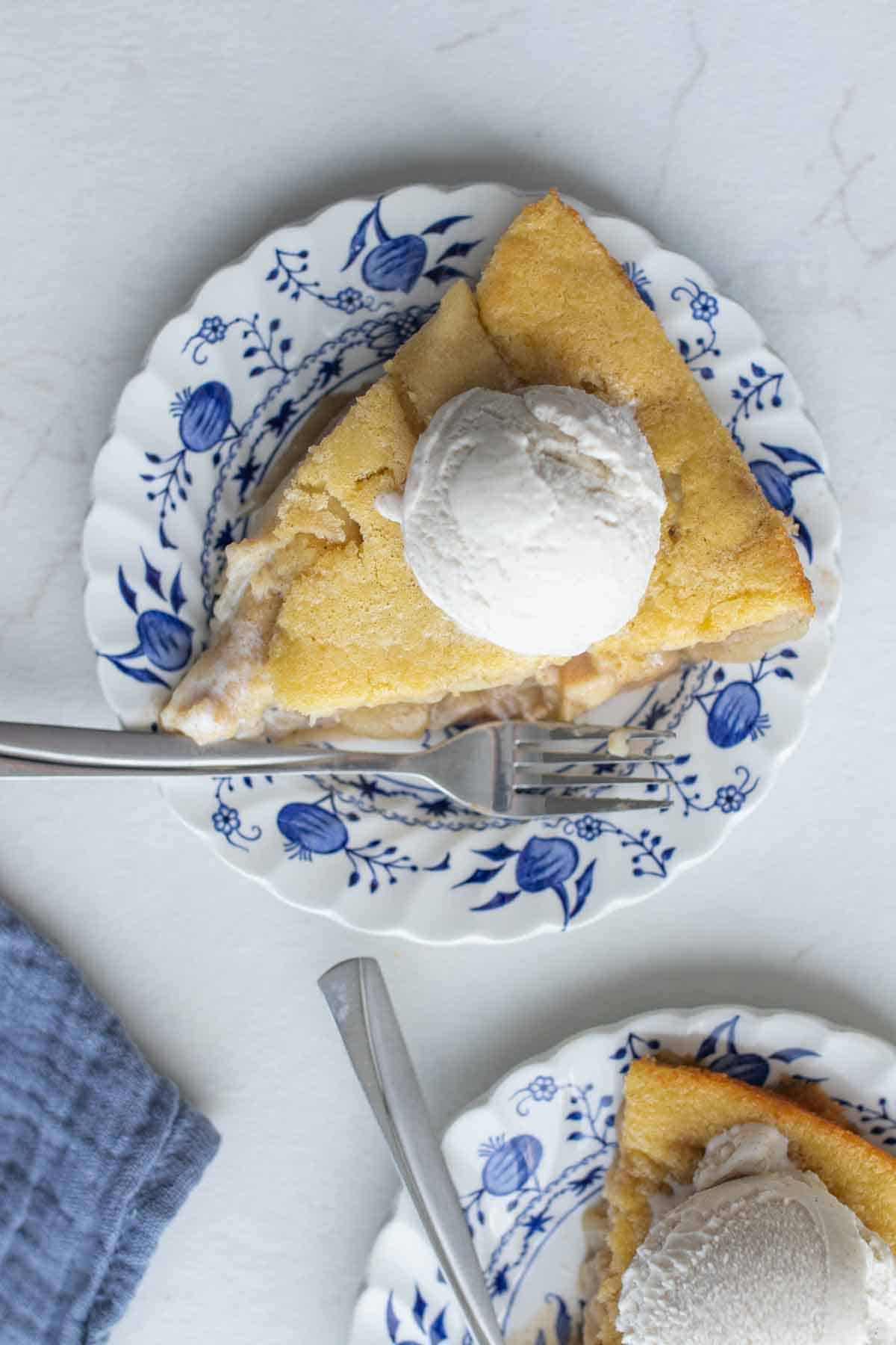 A slice of sourdough apple cobbler with a scoop of ice cream on top on a small saucer plate.