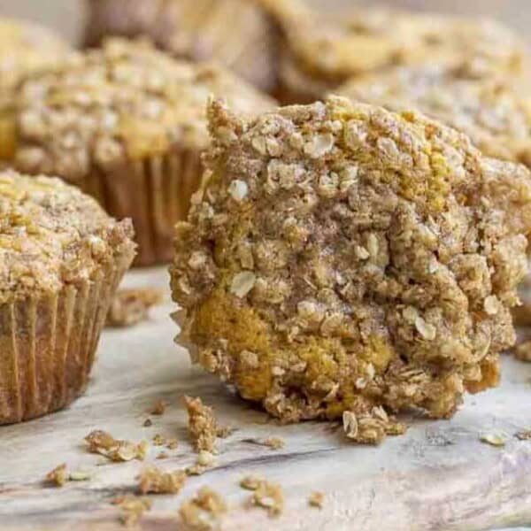 sourdough pumpkin muffins with a crumb topping spread in a wood cutting board on a green towel